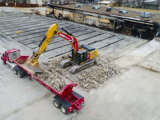 An aerial view of an excavator loading demolition debris into a truck for DeCarlo Demolition Company in Des Moines, IA.