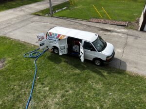 An aerial view of the FM Cleaning van with hoses extended, indicating a cleaning job in progress at a residential site in West Fargo, ND.