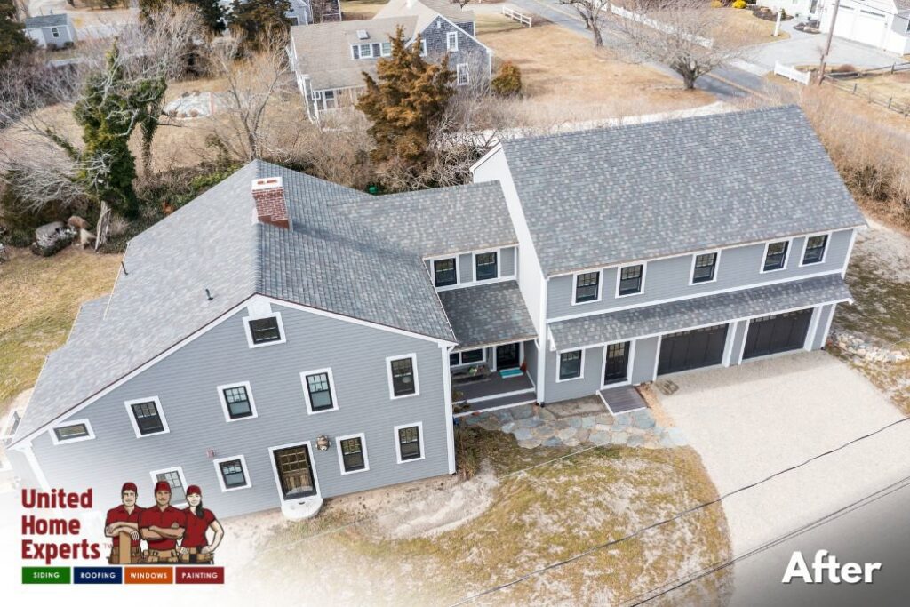 An aerial view of a large grey house with newly installed siding and roofing by United Home Experts in Ashland, MA