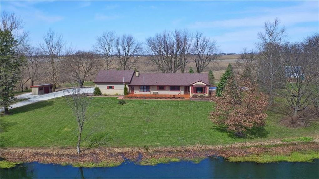 An aerial view of a beautiful, well-maintained residential property with a large green lawn and pond, serviced by Nice & Precise Lawn Care in Ames, IA.