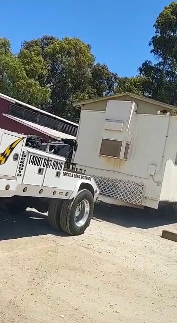 Aguilar Towing's heavy-duty truck towing a small portable building in San Jose, CA
