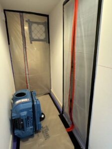 A blue air mover and plastic containment in a hallway for water damage drying by Island Restoration LLC in Kapolei, HI.