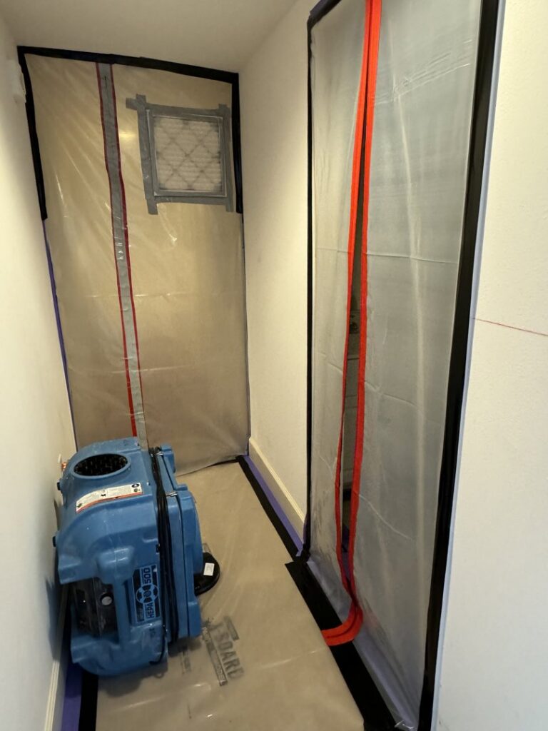 A blue air mover and plastic containment in a hallway for water damage drying by Island Restoration LLC in Kapolei, HI.
