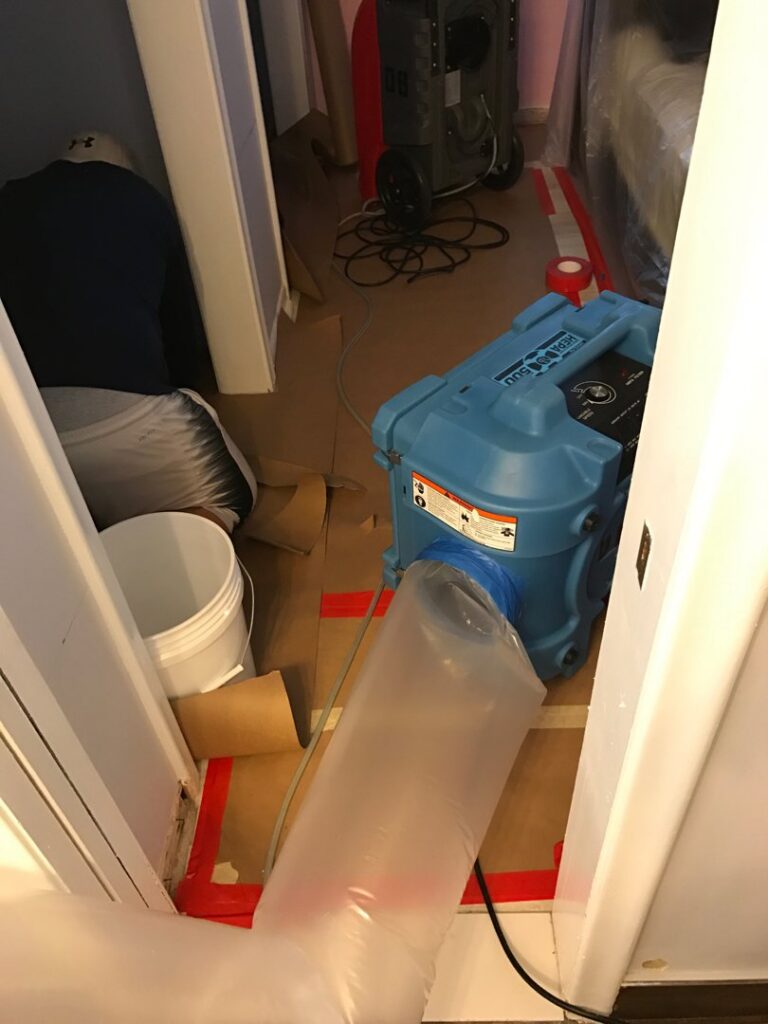 An air mover with a flexible duct and red tape on the floor, indicating water damage drying in progress by Southcoast Cleaning Solutions & Restoration in Fall River, MA.