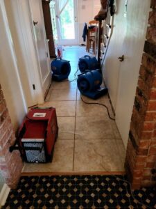 Air movers and dehumidifier drying a tiled hallway after water damage by Belfor Property Restoration, New Orleans, LA