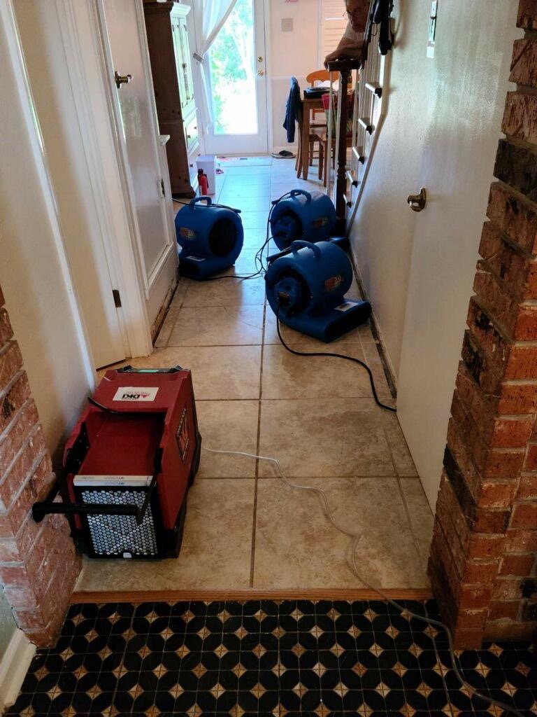 Air movers and dehumidifier drying a tiled hallway after water damage by Belfor Property Restoration, New Orleans, LA