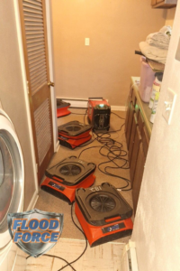Multiple air movers and a dehumidifier set up in a room for water damage drying by Flood Force in Dayton, OH.