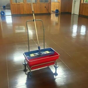 A mop bucket on a wet floor with air movers in the background, indicating water damage drying by Superior Contract Cleaning in Lafayette, LA.