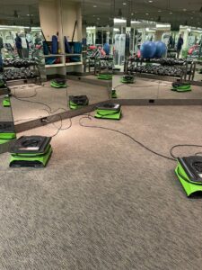 Air movers drying carpet in a gym or fitness center after water damage, by Servpro South Jersey City Bayonne in Jersey City, NJ.