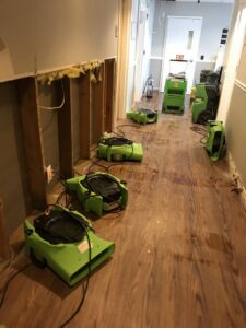 Air movers drying a hallway with exposed wall studs, indicating water damage restoration by Servpro South Jersey City Bayonne in Jersey City, NJ.