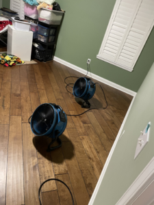 Two air movers drying a hardwood floor as part of water damage restoration by Healthy Interior Solutions in Fishers, IN.