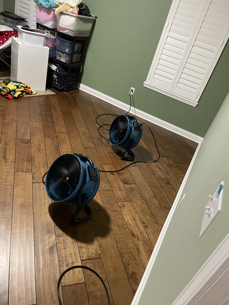 Two air movers drying a hardwood floor as part of water damage restoration by Healthy Interior Solutions in Fishers, IN.