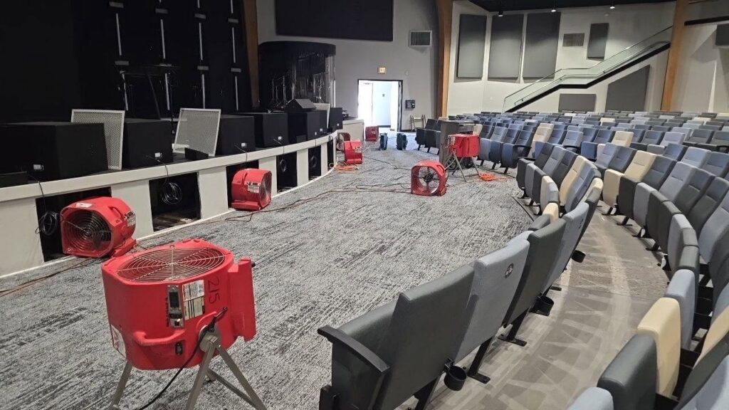 Multiple air movers and drying equipment set up in a large auditorium for water damage restoration by TriForce Restoration in Moore, OK.