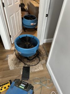 Two industrial air movers drying a water-damaged floor with removed sections during restoration by Prime Restoration in Lancaster, PA.