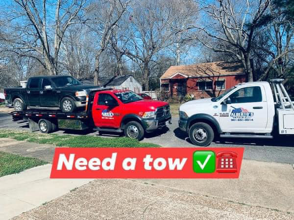 Two Alberto Junk Removal tow trucks, a red flatbed with a pickup and a white wrecker, in Memphis, TN.