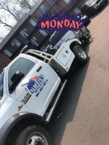 A white wrecker tow truck from Alberto Junk Removal actively towing a car in Memphis, TN.