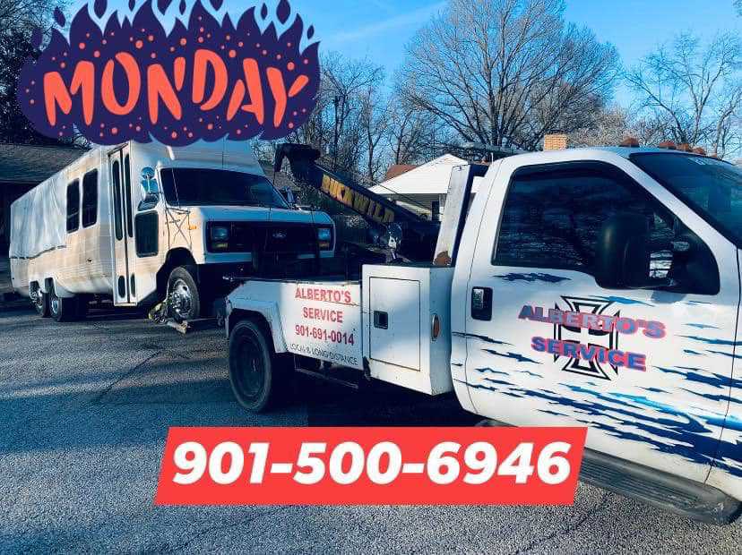 A white wrecker tow truck from Alberto Junk Removal towing a large RV or bus in Memphis, TN.