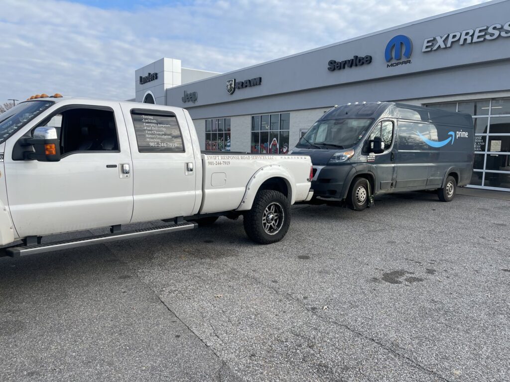 An Amazon Prime delivery van being towed by a white pickup truck, showcasing towing services by Swift Response Road Services, LLC in Memphis, TN.