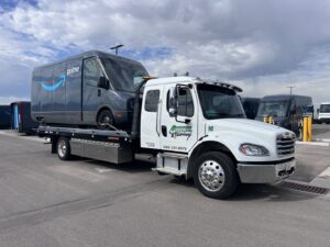 An Amazon Prime delivery van being transported on a flatbed tow truck by 4 Wheel Towing in South Salt Lake, UT.