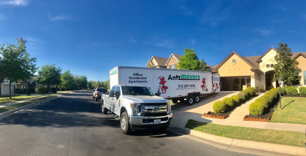 An Antz Movers Company truck and trailer parked in front of a residential home, ready for a move in Austin, TX.