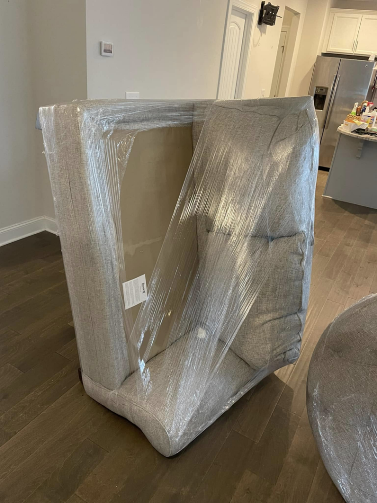 An armchair securely wrapped in clear plastic for protection during a move by CNZ Moving in Raleigh, NC.