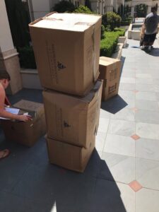 Several Armstrong Relocation branded moving boxes stacked outside a building, ready for transport by The Armstrong Company in Huntsville, AL.