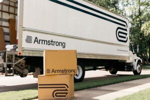 An Armstrong moving truck with branded moving boxes on the ground, ready for a move by The Armstrong Company in Huntsville, AL.