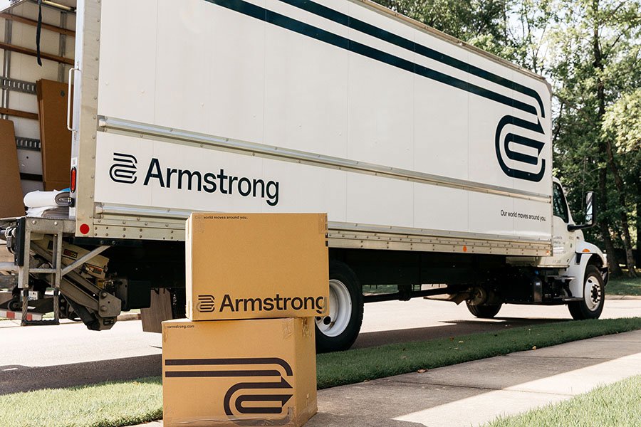 An Armstrong moving truck with branded moving boxes on the ground, ready for a move by The Armstrong Company in Huntsville, AL.