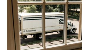 A white Armstrong moving truck parked outside, viewed through a window, for The Armstrong Company in Huntsville, AL.
