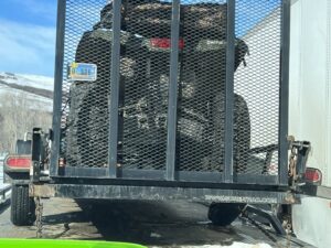 An ATV on a trailer being loaded onto a flatbed tow truck by Carnahan's Towing & Repair Inc. in Great Falls, MT.