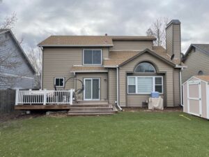 Rear of a house with new tan horizontal siding and a wooden deck, completed by EZ General Construction in Colorado Springs, CO.