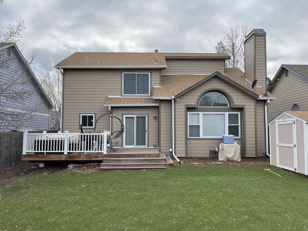 Rear of a house with new tan horizontal siding and a wooden deck, completed by EZ General Construction in Colorado Springs, CO.