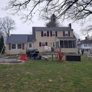 The back of a residential house featuring new yellow siding installed by Trabajo en roofing y siding in Lowell, MA.