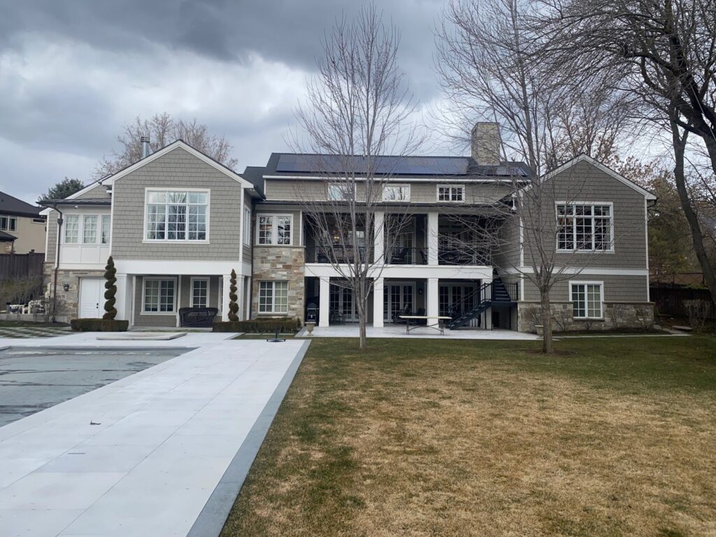 The rear view of a large house showcasing gray horizontal siding and stone accents by New Look Siding in Midvale, UT.