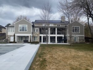 The rear view of a large house showcasing gray horizontal siding and stone accents by New Look Siding in Midvale, UT.