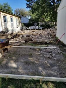 A backyard showing concrete rubble from a demolished patio or foundation by Vaquero Demolition in Lewisville, TX.