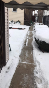 A cleared concrete path leading to a backyard after snow removal by Apolonio's Snow Removal and Lawn care in Chicago, IL.
