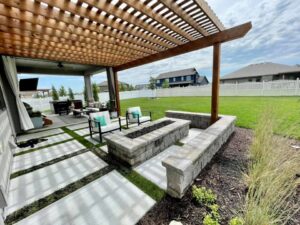 A modern backyard patio with a pergola and fire pit, featuring a lush green lawn maintained by Mitera Landscaping in Papillion, NE.