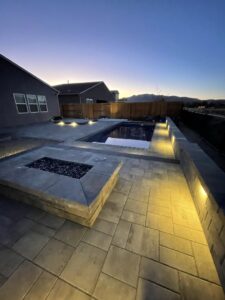 A beautifully designed backyard with a swimming pool, fire pit, and ambient lighting by Battle Born Pool & Spa in Sparks, NV.