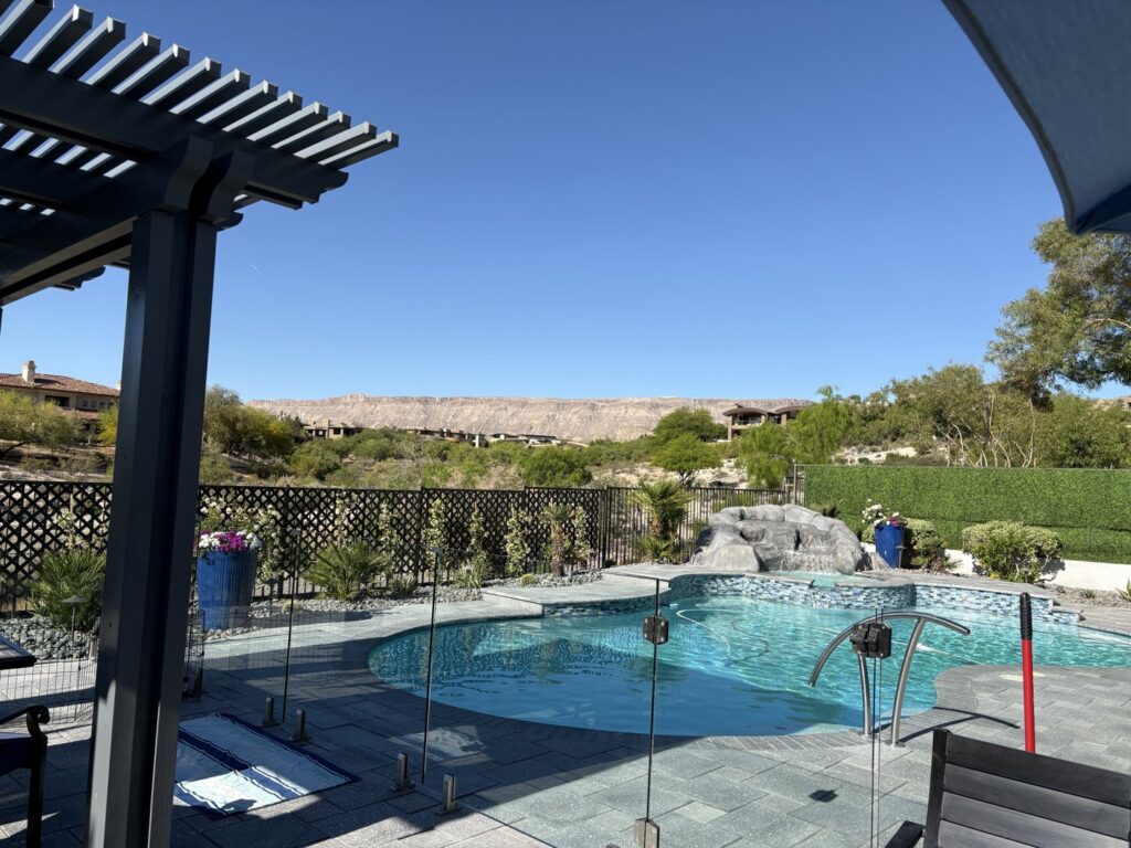 A backyard pool featuring a rock waterfall and surrounding patio by Laguna Pool & Spa and Landscaping in Las Vegas, NV