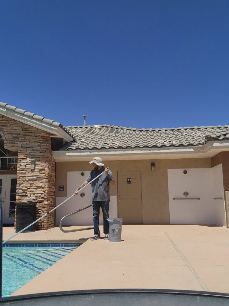 A backyard swimming pool with a cleaning hose visible, demonstrating service by Priority Pools LV in Las Vegas, NV