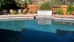 A beautifully maintained backyard swimming pool with a water feature and brick coping by Lifestyle Pool & Spa in Reno, NV