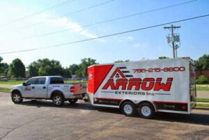 A barn featuring newly installed gray horizontal siding and distinctive red doors by Arrow Exteriors Inc. in Topeka, KS