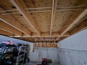 An exposed basement ceiling with a drying fan, showing water damage remediation by PuroClean of Strafford County in Nottingham, NH.