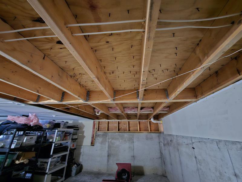 An exposed basement ceiling with a drying fan, showing water damage remediation by PuroClean of Strafford County in Nottingham, NH.