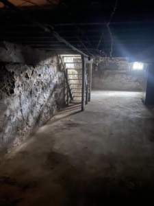 Basement demolition showing exposed stone walls and ceiling joists, a project by Identical Demolition LLC in Philadelphia, PA.