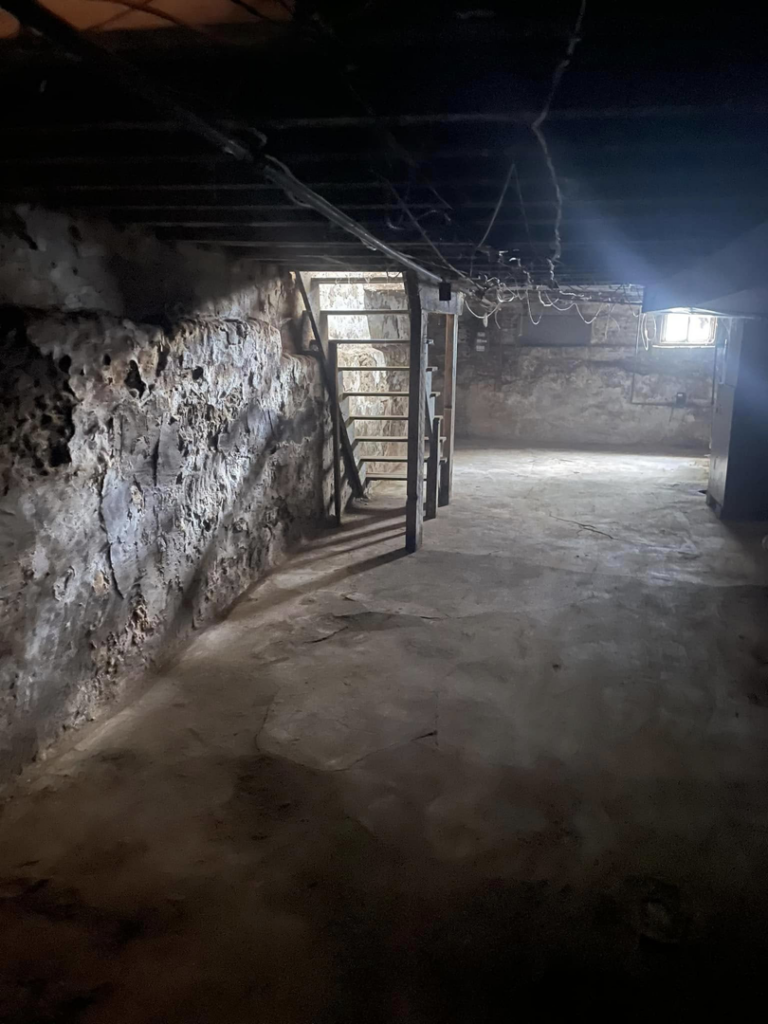Basement demolition showing exposed stone walls and ceiling joists, a project by Identical Demolition LLC in Philadelphia, PA.
