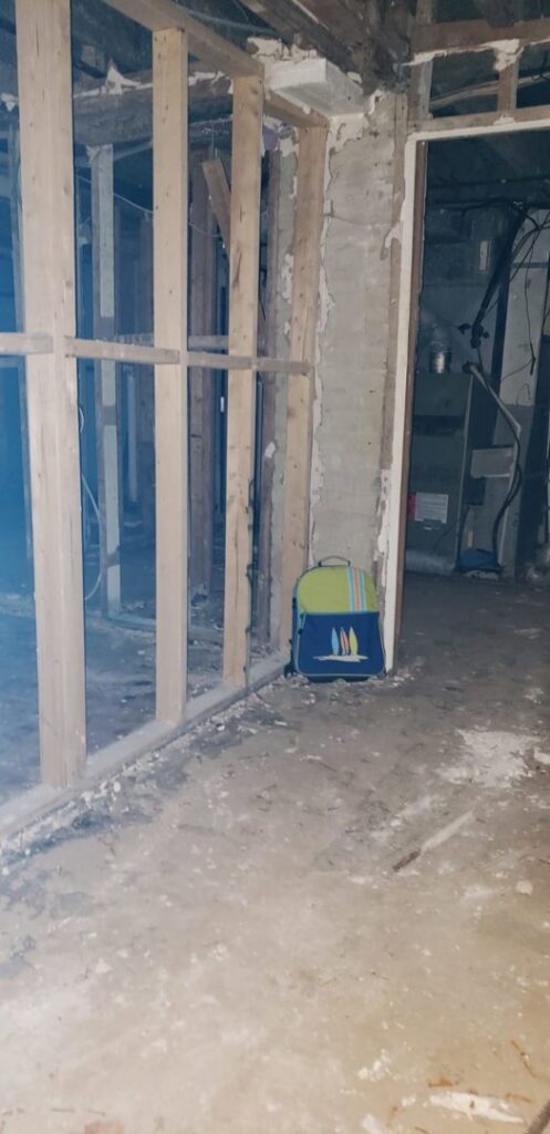 A basement room with exposed studs and concrete floor during water damage remediation by GOD'S GLORY LLC in Bowie, MD.