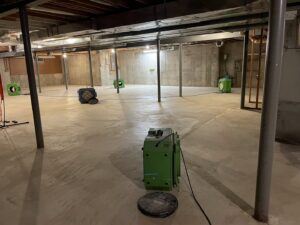 Multiple air movers and dehumidifiers set up in a basement for water damage restoration by NSH Home Services in Jersey City, NJ.