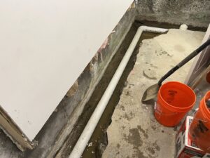 An interior basement drainage pipe being installed in a trench by EFFECTIVE WATERPROOFING in Worcester, MA.